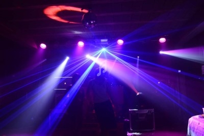 Jeune personne dans une salle sombre éclairée par des faisceaux lumineux colorés et une boule disco au plafond.