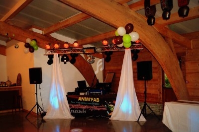 Installation de matériel de sonorisation et d'éclairage pour une soirée dans une salle en bois avec décoration festive.