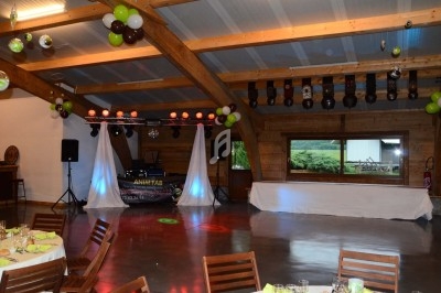 Salle de réception décorée avec des ballons, tables dressées et une scène équipée pour des animations musicales.