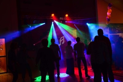 Des personnes dansent dans une salle sombre éclairée par des lumières colorées de projecteurs.