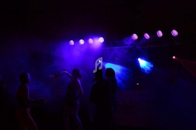 Un homme chante sur scène avec un micro, éclairé par une lumière rouge dans une ambiance de concert.