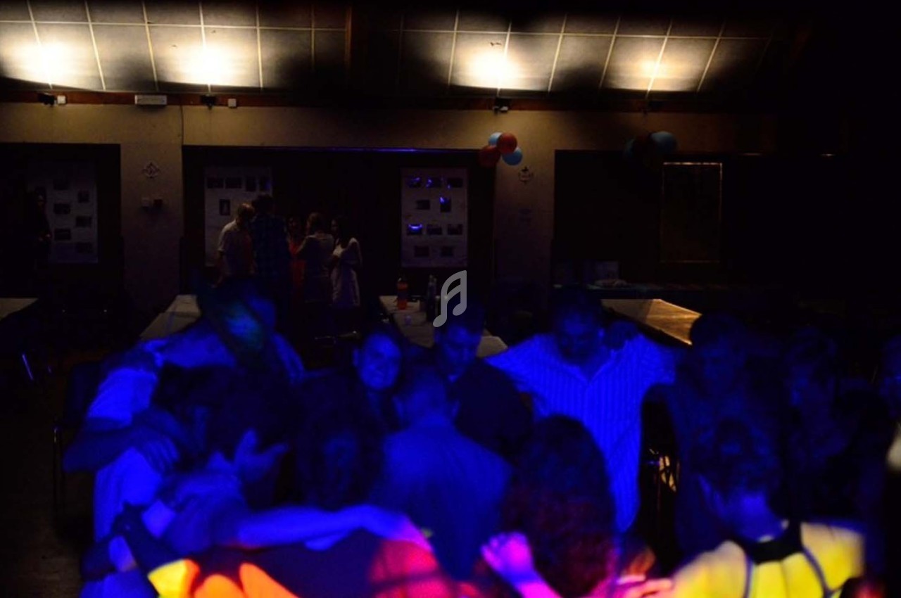 Groupe de personnes dans une salle faiblement éclairée, éclairée par des lumières colorées lors d'un événement festif.