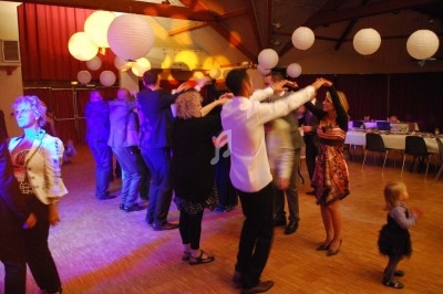 Un homme chante sur scène avec un micro, éclairé par une lumière rouge dans une ambiance de concert.