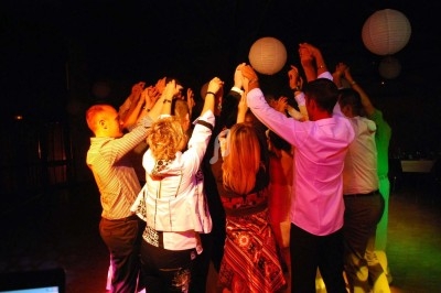 Un homme chante sur scène avec un micro, éclairé par une lumière rouge dans une ambiance de concert.