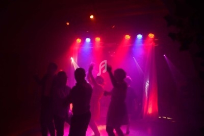 Un homme chante sur scène avec un micro, éclairé par une lumière rouge dans une ambiance de concert.