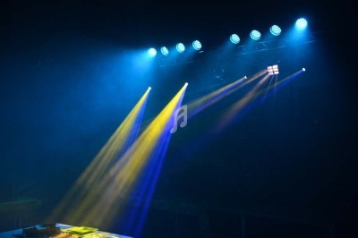 Un homme chante sur scène avec un micro, éclairé par une lumière rouge dans une ambiance de concert.