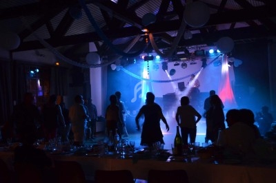 Un homme chante sur scène avec un micro, éclairé par une lumière rouge dans une ambiance de concert.