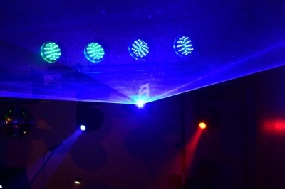 Un homme chante sur scène avec un micro, éclairé par une lumière rouge dans une ambiance de concert.