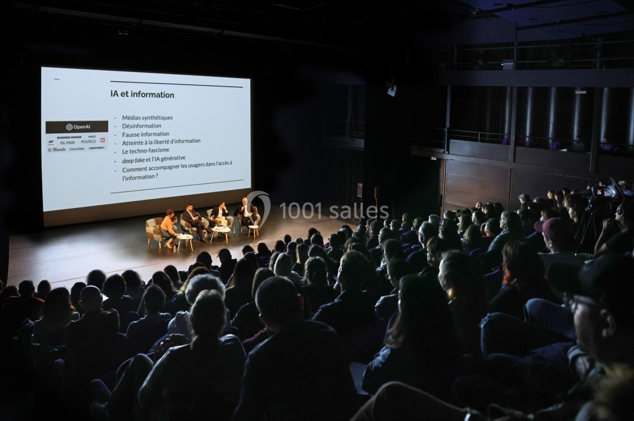 Conférence sur l'intelligence artificielle et l'information, avec des intervenants sur scène face à un public attentif.