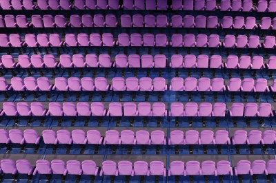 Salle de spectacle vide avec des rangées de sièges violets face à une scène sombre.
