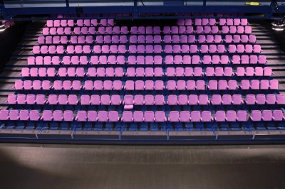Salle de spectacle vide avec des rangées de sièges violets face à une scène sombre.