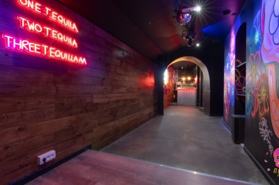 Autocollants colorés de motifs mexicains sur une porte vitrée, avec un crâne rose et l'inscription ’El Cartel Pigalle’.