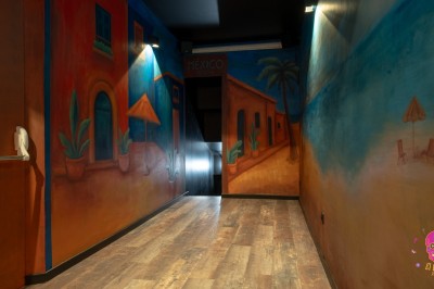 Autocollants colorés de motifs mexicains sur une porte vitrée, avec un crâne rose et l'inscription ’El Cartel Pigalle’.