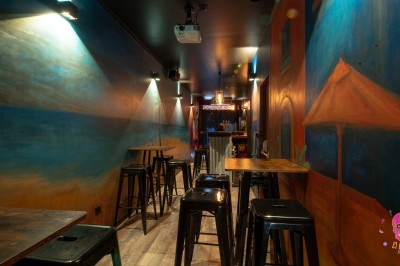 Autocollants colorés de motifs mexicains sur une porte vitrée, avec un crâne rose et l'inscription ’El Cartel Pigalle’.