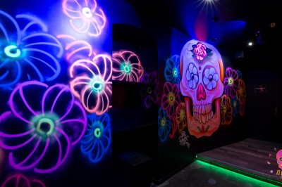 Autocollants colorés de motifs mexicains sur une porte vitrée, avec un crâne rose et l'inscription ’El Cartel Pigalle’.