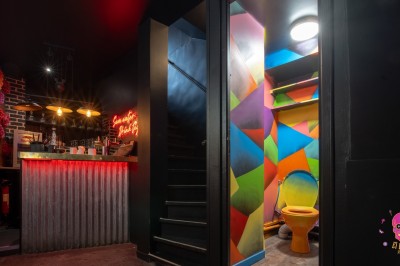 Autocollants colorés de motifs mexicains sur une porte vitrée, avec un crâne rose et l'inscription ’El Cartel Pigalle’.