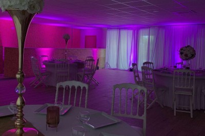 Terrain de pétanque intérieur avec sol en sable, encadré de murs en tôle et briques, à côté d'un espace détente.