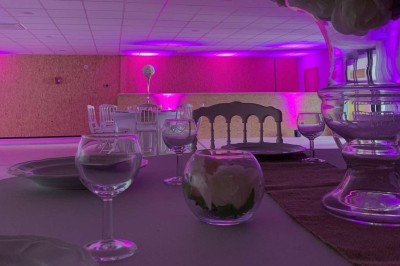 Terrain de pétanque intérieur avec sol en sable, encadré de murs en tôle et briques, à côté d'un espace détente.