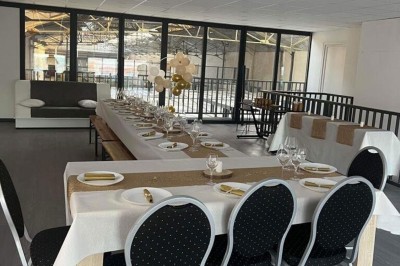 Terrain de jeu en sable couvert, entouré de cloisons métalliques, avec des équipements et sièges à proximité.