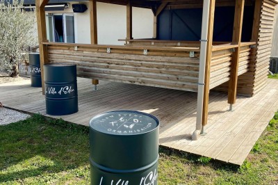 Piscine éclairée de nuit avec des lumières rouges et violettes, entourée de palmiers et d'une table avec un verre.
