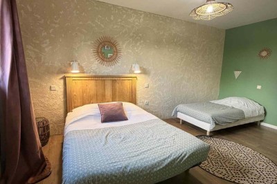 Des personnes discutent debout autour de tables en bois devant des tentes blanches dans un espace extérieur arboré.