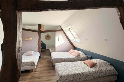 Des personnes discutent debout autour de tables en bois devant des tentes blanches dans un espace extérieur arboré.