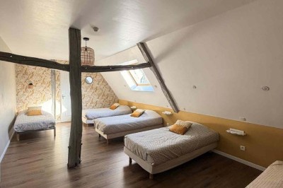 Des personnes discutent debout autour de tables en bois devant des tentes blanches dans un espace extérieur arboré.