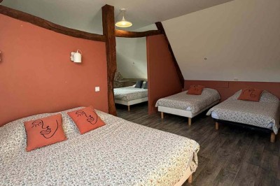 Des personnes discutent debout autour de tables en bois devant des tentes blanches dans un espace extérieur arboré.