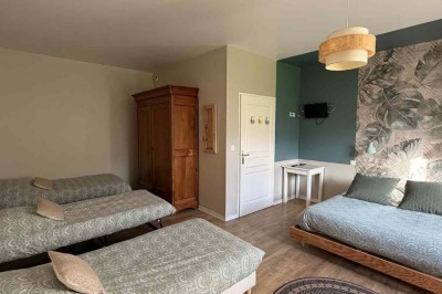 Des personnes discutent debout autour de tables en bois devant des tentes blanches dans un espace extérieur arboré.