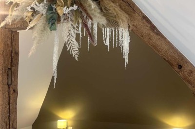 Des personnes discutent debout autour de tables en bois devant des tentes blanches dans un espace extérieur arboré.