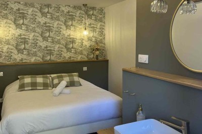 Des personnes discutent debout autour de tables en bois devant des tentes blanches dans un espace extérieur arboré.