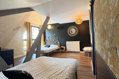 Des personnes discutent debout autour de tables en bois devant des tentes blanches dans un espace extérieur arboré.