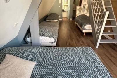 Des personnes discutent debout autour de tables en bois devant des tentes blanches dans un espace extérieur arboré.