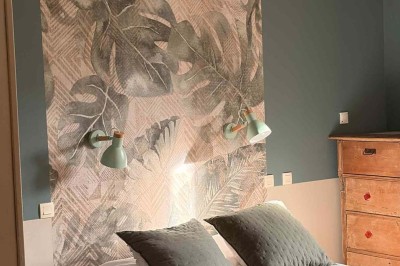 Des personnes discutent debout autour de tables en bois devant des tentes blanches dans un espace extérieur arboré.