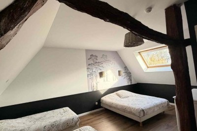 Des personnes discutent debout autour de tables en bois devant des tentes blanches dans un espace extérieur arboré.