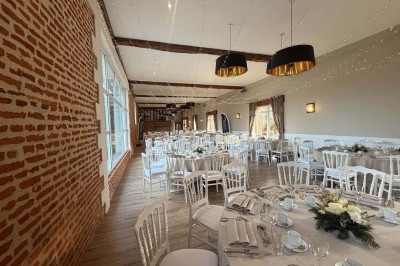 Des personnes discutent debout autour de tables en bois devant des tentes blanches dans un espace extérieur arboré.