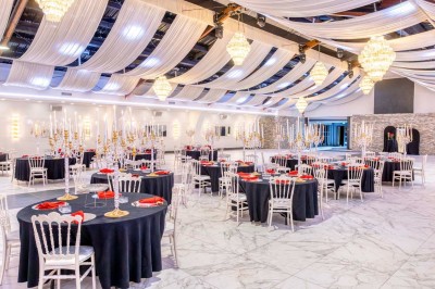 Cuisine professionnelle moderne avec équipements en inox, éclairage suspendu et fourneaux sous une hotte d'extraction.