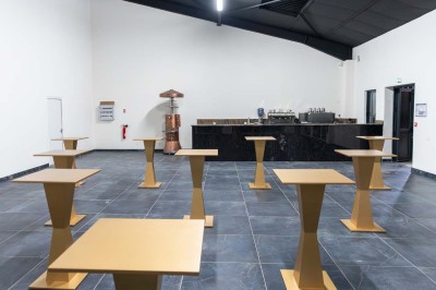 Cuisine professionnelle moderne avec équipements en inox, éclairage suspendu et fourneaux sous une hotte d'extraction.