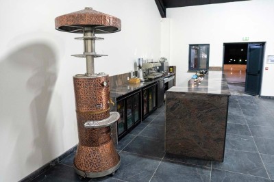 Cuisine professionnelle moderne avec équipements en inox, éclairage suspendu et fourneaux sous une hotte d'extraction.