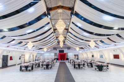 Cuisine professionnelle moderne avec équipements en inox, éclairage suspendu et fourneaux sous une hotte d'extraction.