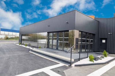 Cuisine professionnelle moderne avec équipements en inox, éclairage suspendu et fourneaux sous une hotte d'extraction.