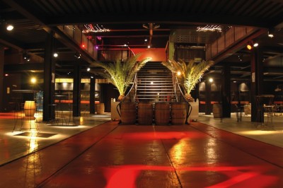 Foule dans une salle sombre éclairée par des lumières rouges intenses, avec une scène visible au fond.