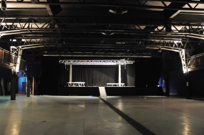 Foule dans une salle sombre éclairée par des lumières rouges intenses, avec une scène visible au fond.