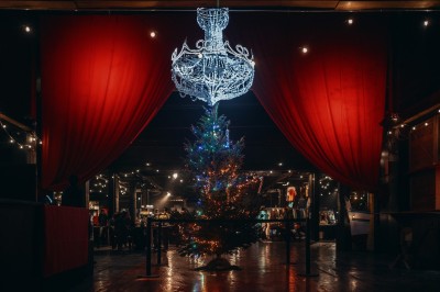 Foule dans une salle sombre éclairée par des lumières rouges intenses, avec une scène visible au fond.