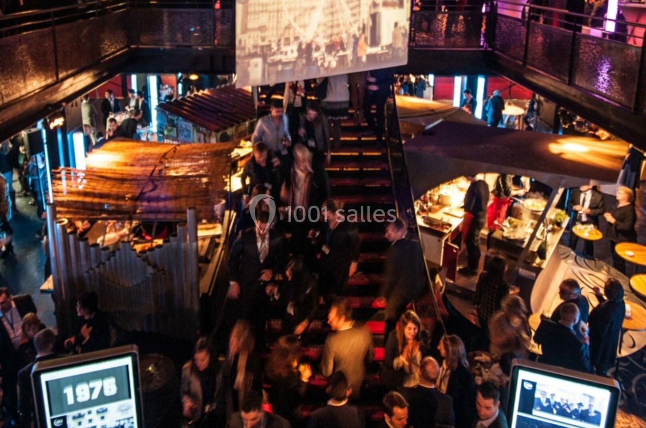 Foule rassemblée dans un espace événementiel animé avec éclairage coloré et stands de restauration.