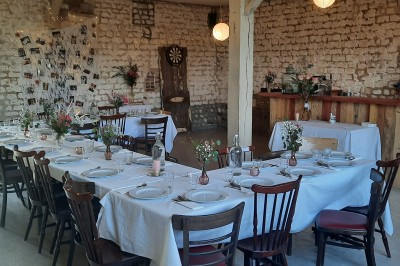 Terrasse aménagée avec tables, chaises et parasols devant une maison en pierre, entourée de verdure.