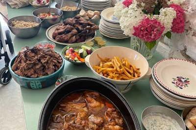Terrasse aménagée avec tables, chaises et parasols devant une maison en pierre, entourée de verdure.