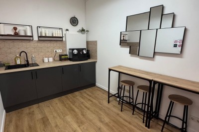 Cuisine moderne avec évier, machine à café automatique, bouilloire et étagères murales décorées.