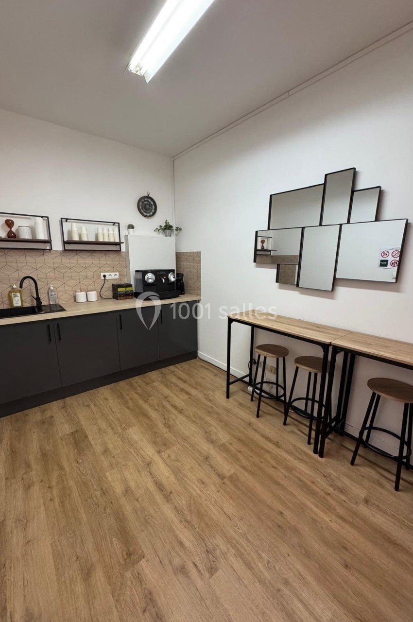 Cuisine moderne avec plancher en bois, comptoirs noirs, étagères ouvertes, tabourets hauts et miroirs géométriques.