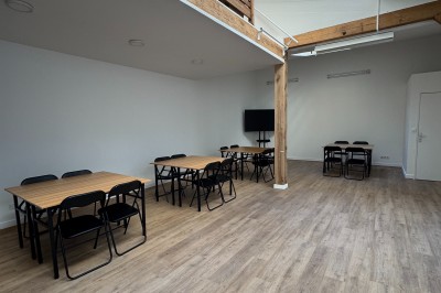Intérieur d'une pièce lumineuse avec parquet, poutres en bois, verrière et mezzanine.